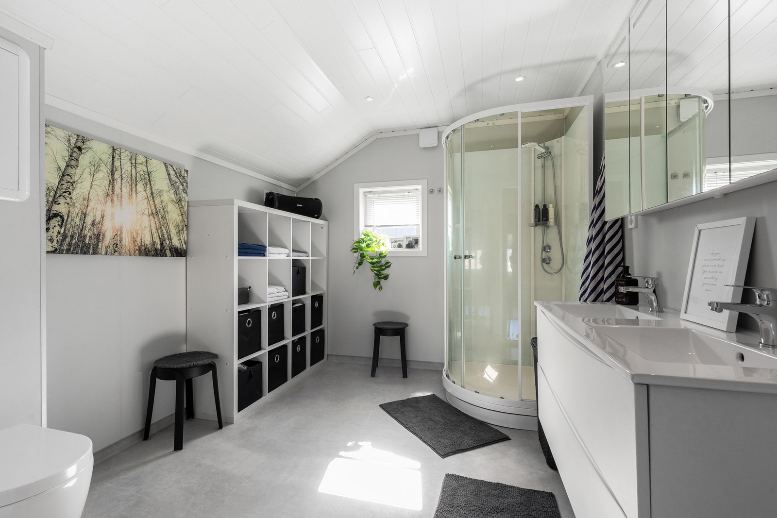 Delikat og tidløst baderom bestående av servant med underskuffer, vegghengt toalett og dusjkabinett Galleribilde