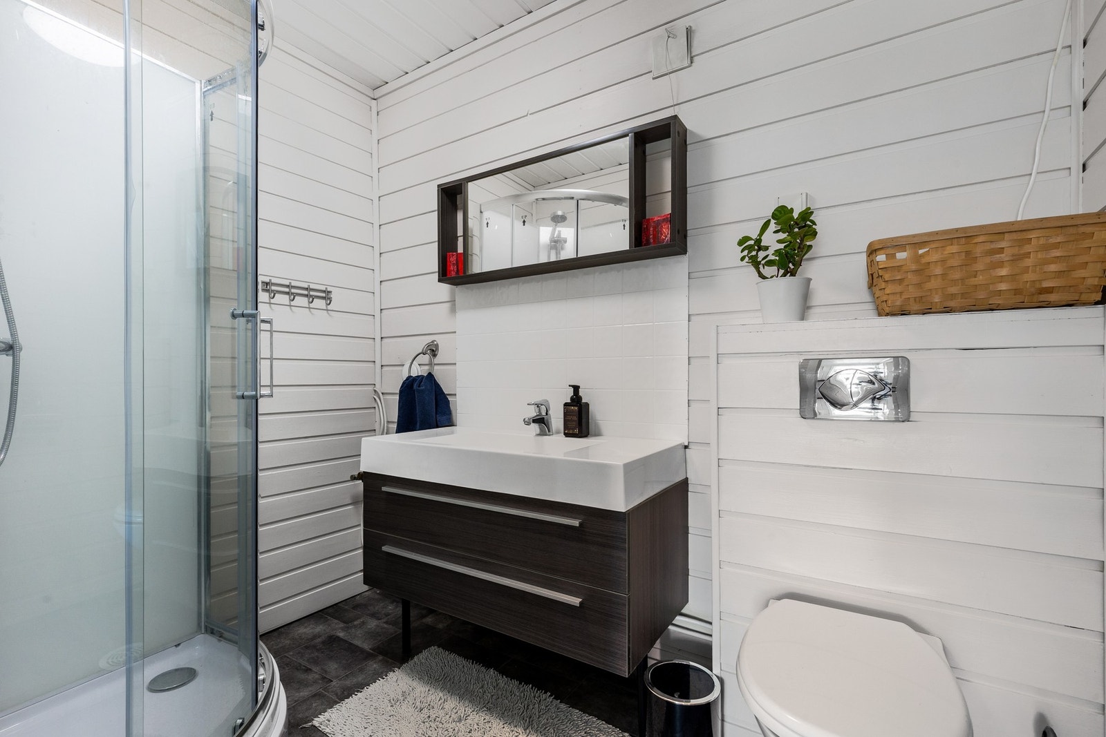 Baderommet i hovedetasjen er bestående av servant med underskuffer, dusjkabinett og vegghengt toalett Galleribilde