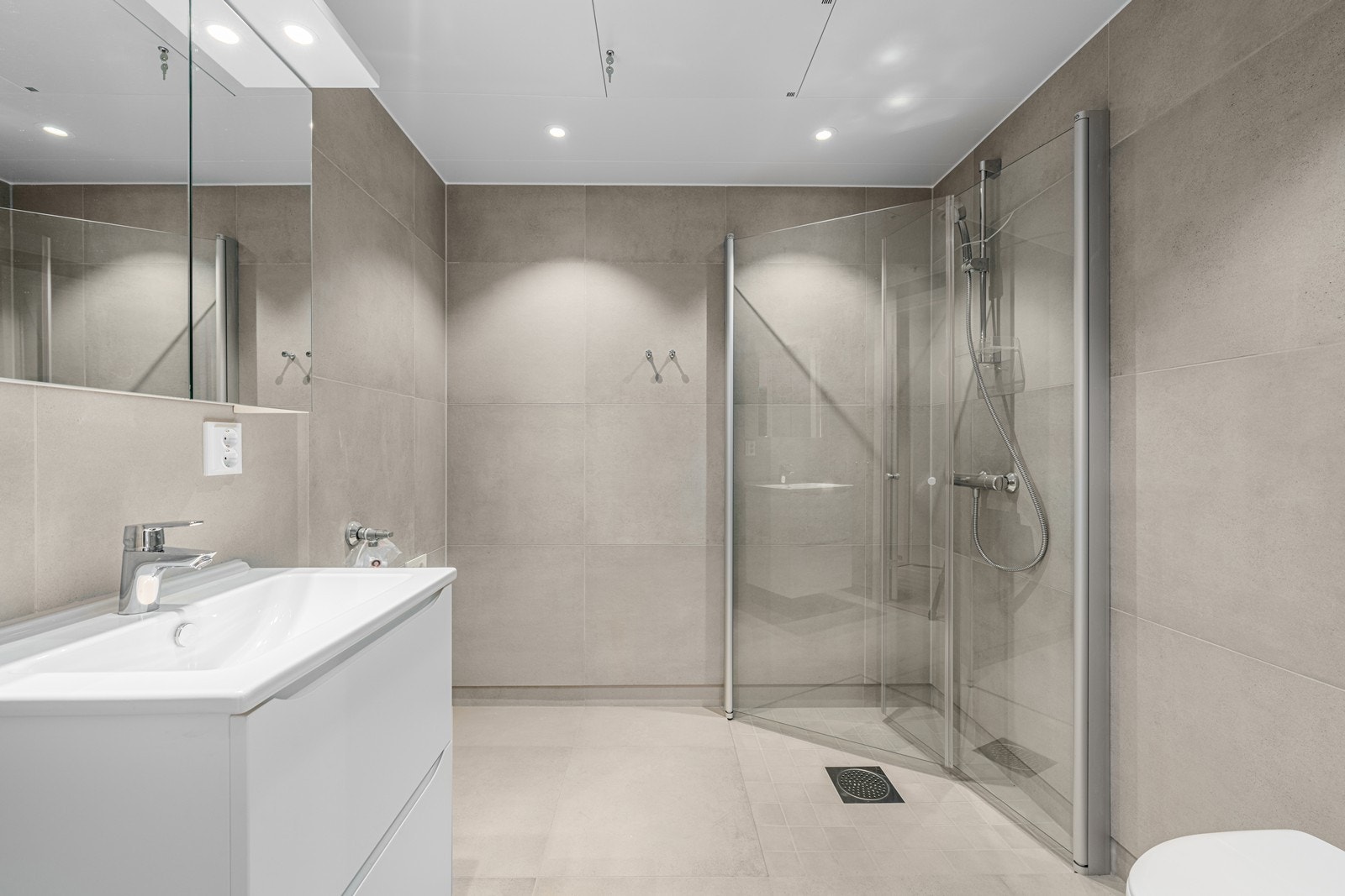 Lekkert baderom med 60x60 fliser på gulv og vegger. I dusjsone er det 10x10 fliser. Galleribilde