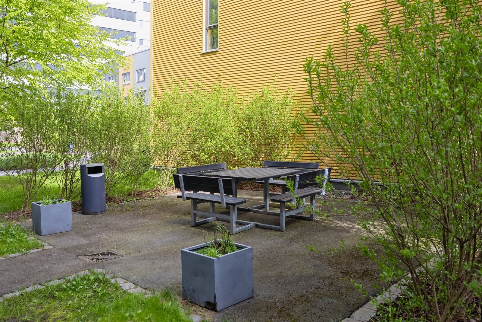 Stor bakgård med sittegrupper, pel og beplantning Galleribilde