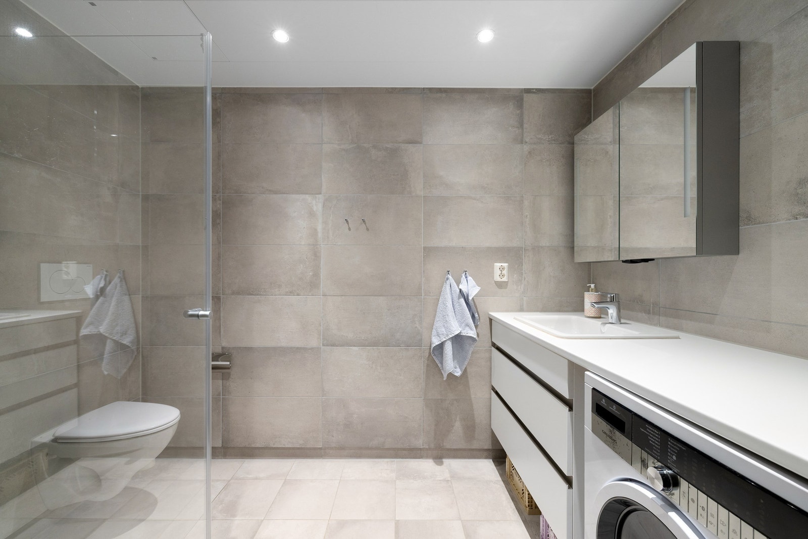 Badet er smart innredet og delikat med fliser i grå nyanser på både gulvet og veggene. Galleribilde