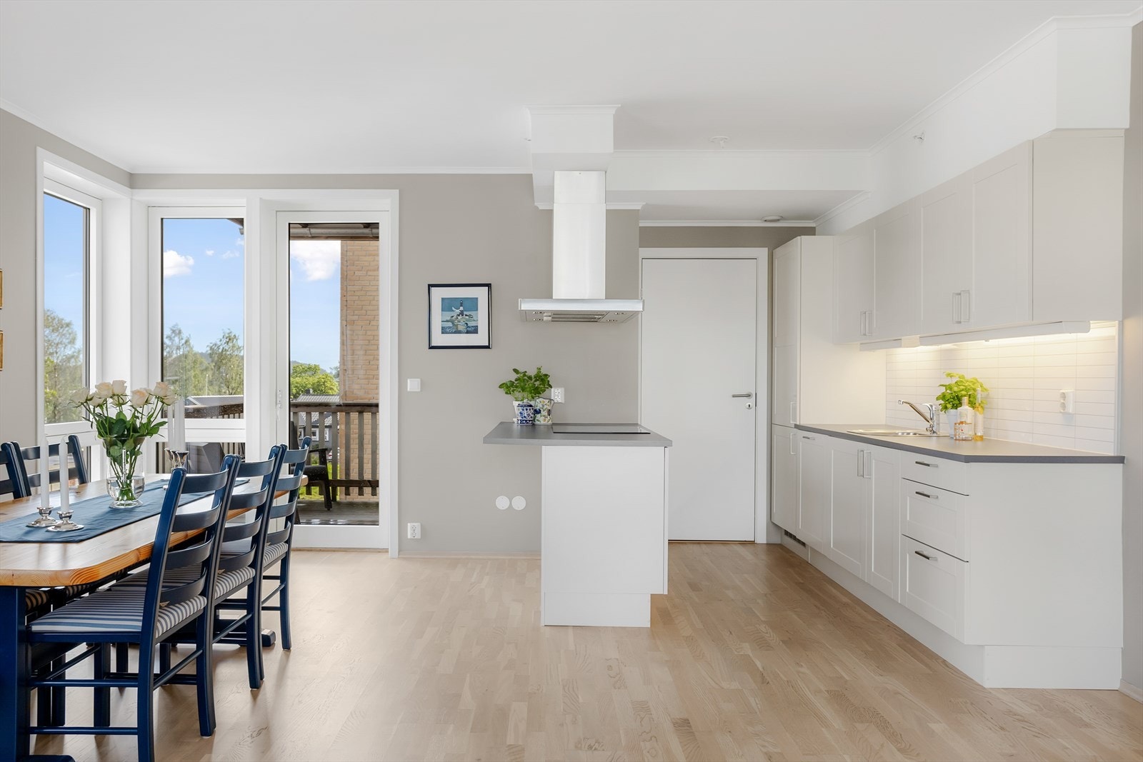 Lyst og luftig kjøkken med åpen planløsning. Moderne innredning i hvitt med gode arbeidsflater. Store vinduer gir rikelig med naturlig lys og vakker utsikt fra balkong. Perfekt for sosiale sammenkomster. Galleribilde