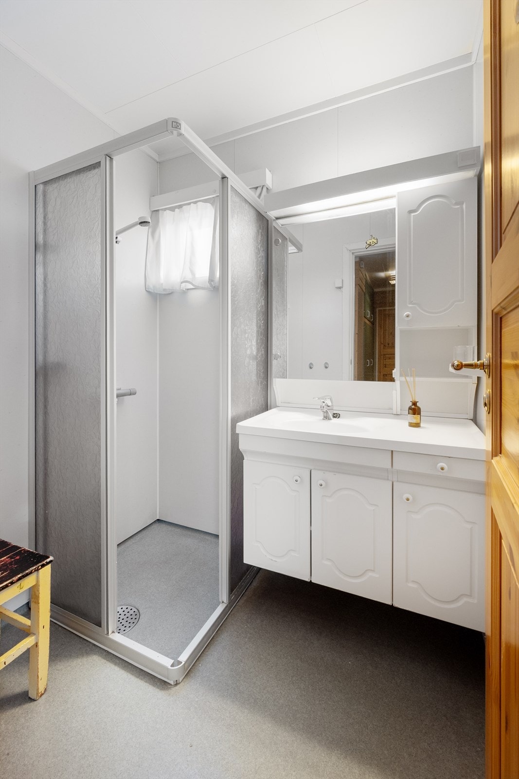 Badet har enkel standard m/baderomsplater og gulvbelegg, samt gulvvarme. Rommet må oppgraderes for å tåle normal bruk etter dagens krav. Galleribilde