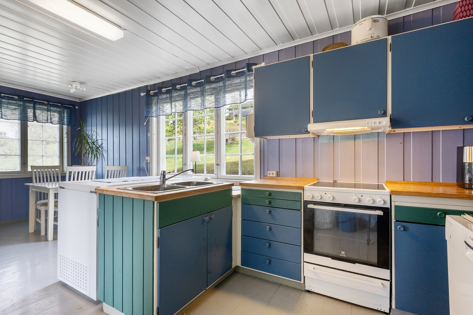 Kjøkkenet har panelvegger malt i blått, og innredning fra 80-tallet. Galleribilde