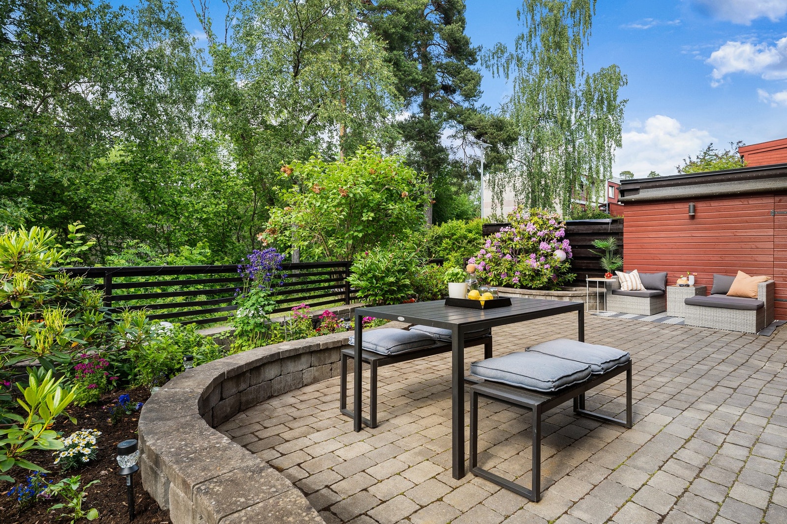 Markterrassen er opparbeidet i flere nivåer, med buet støttemur av betongstein som rammer inn beplantede bed med prydbusker og blomster. Terrasseområdet er skjermet med gjerde, og det er adkomst til praktisk sportsbod. Galleribilde