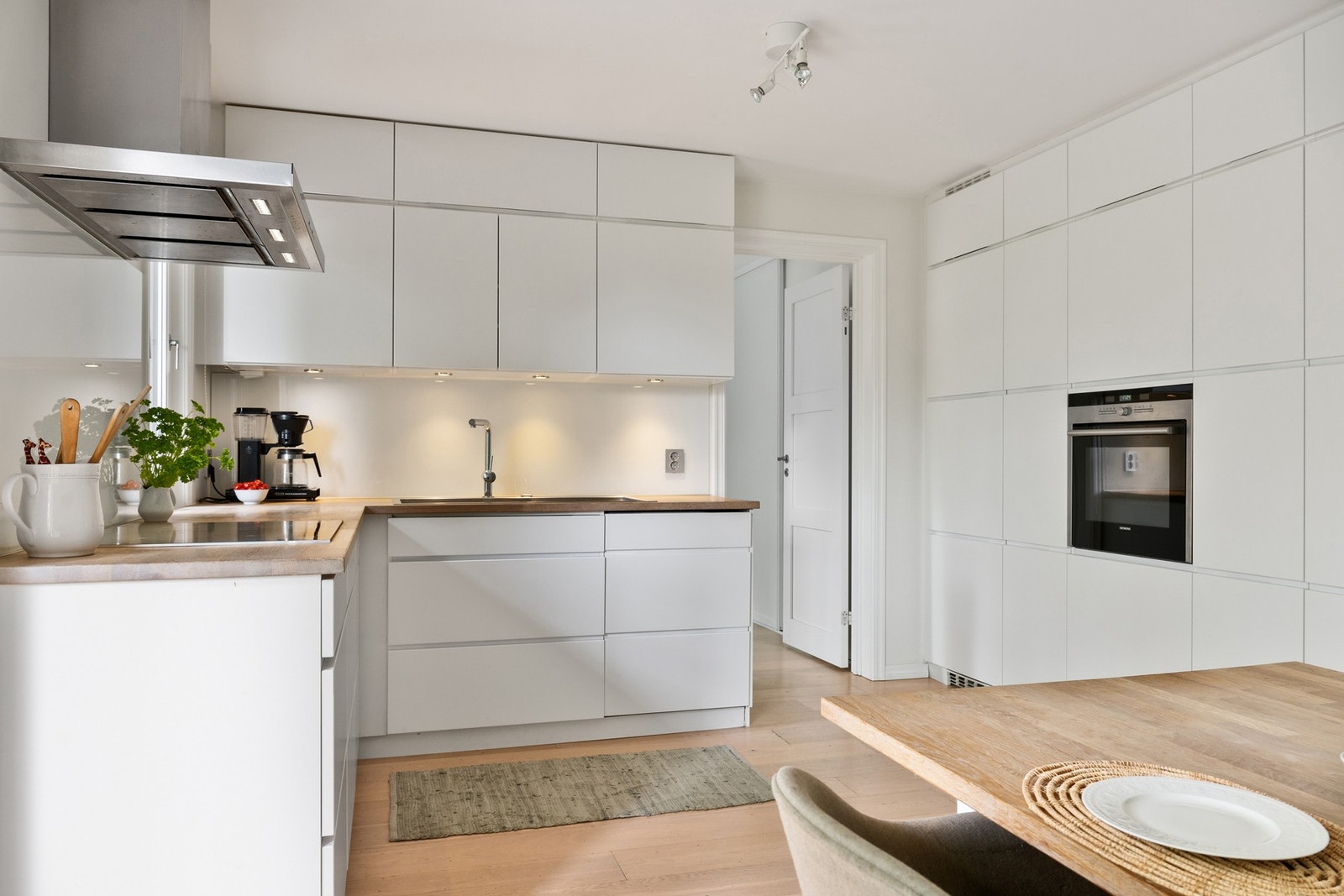 Stilren innredning fra Kvik med takhøye skap, hvite glatte fronter og benkeplate i heltre. Galleribilde