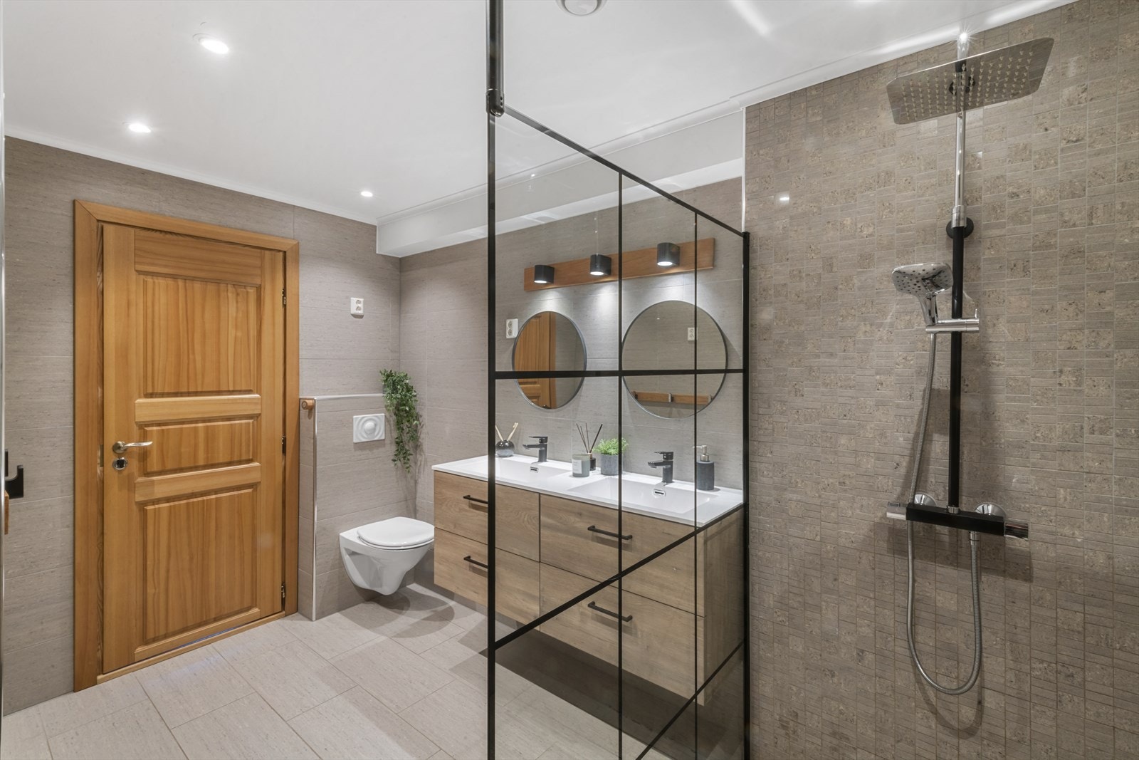 Rommet er utstyrt med moderne innredning som inkluderer to nedfelte servanter med god oppbevaringsplass, veggmontert toalett, to speil og en romslig dusjnisje. Galleribilde