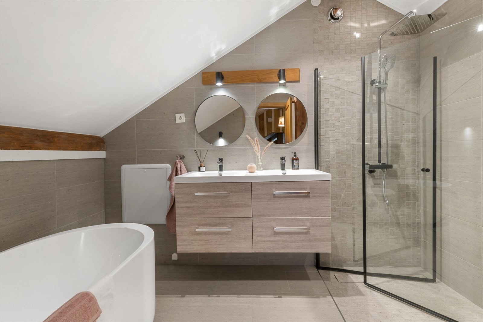 Baderommet i 2. etasje fremstår som svært delikat og gjennomført med moderne løsninger og kvalitetsmaterialer. Veggene er kledd med stilrene fliser, og taket er malt i en lys tone som gir rommet en luftig og behagelig følelse. Galleribilde