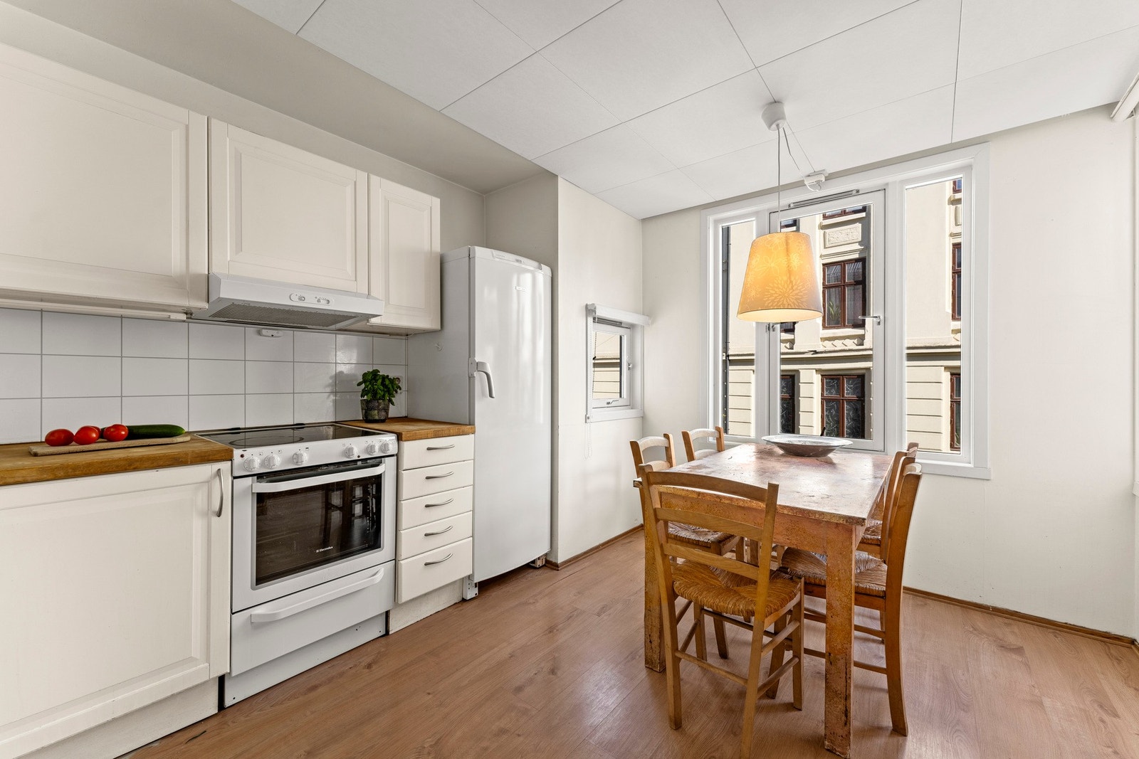 Praktisk kjøkken med god skap- og benkeplass innredet med profilerte fronter og benkeplate i heltre. Vegg over benkeskap er dekket med plater i flismønster. Galleribilde