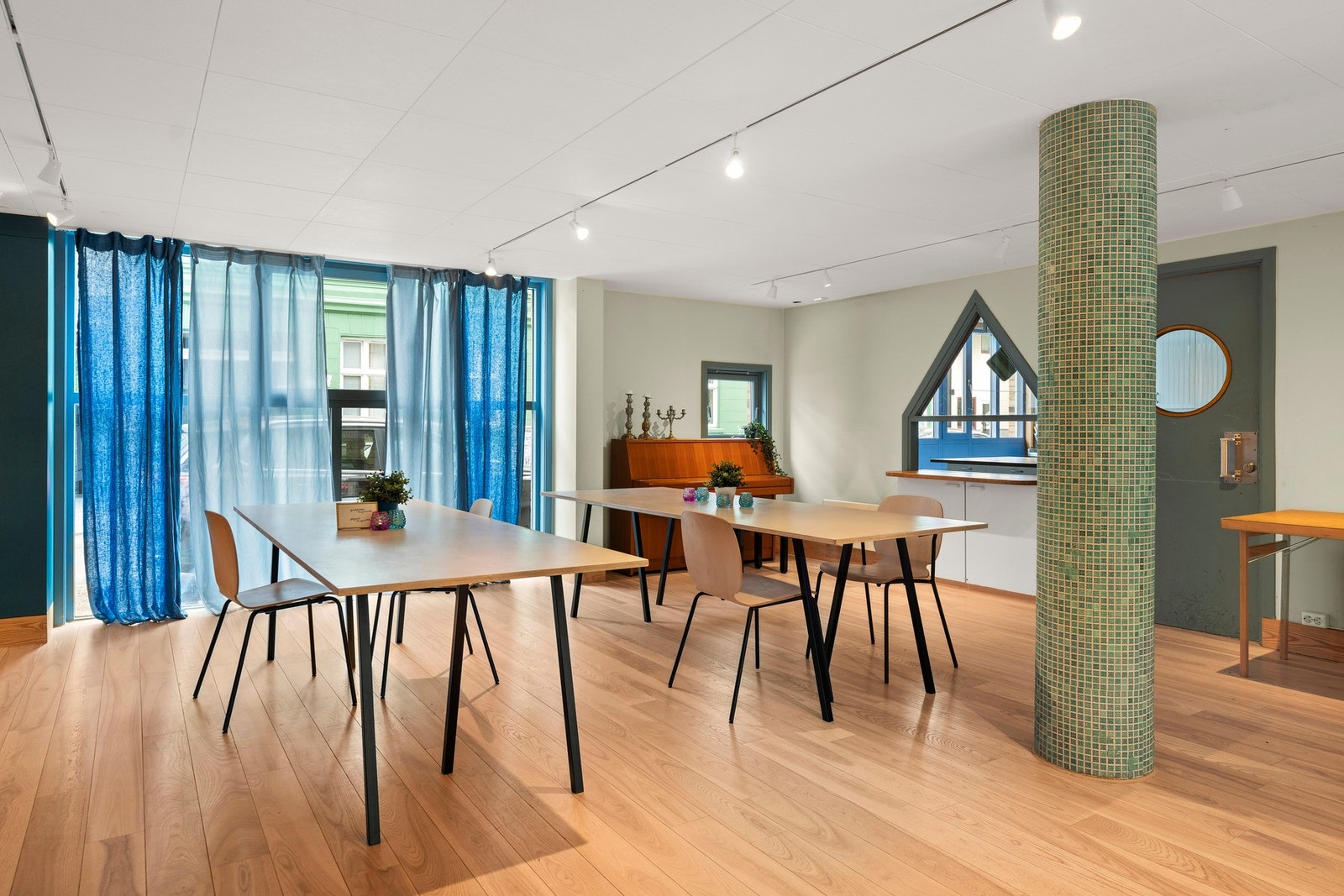 Lyst fellesrom med spiseplasser, piano og "barløsning" via kjøkkenet. Galleribilde