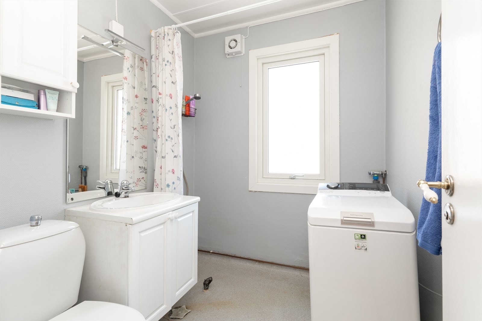 Badet er innredet med toalett, dusj med forheng og servantmøbel med underskap og speil med overlys. Det er opplegg for vaskemaskin. Galleribilde