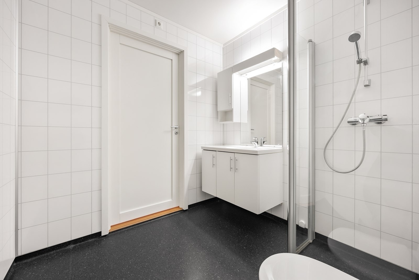Pent baderom med belegg på gulv og våtromsplater på vegg. Galleribilde