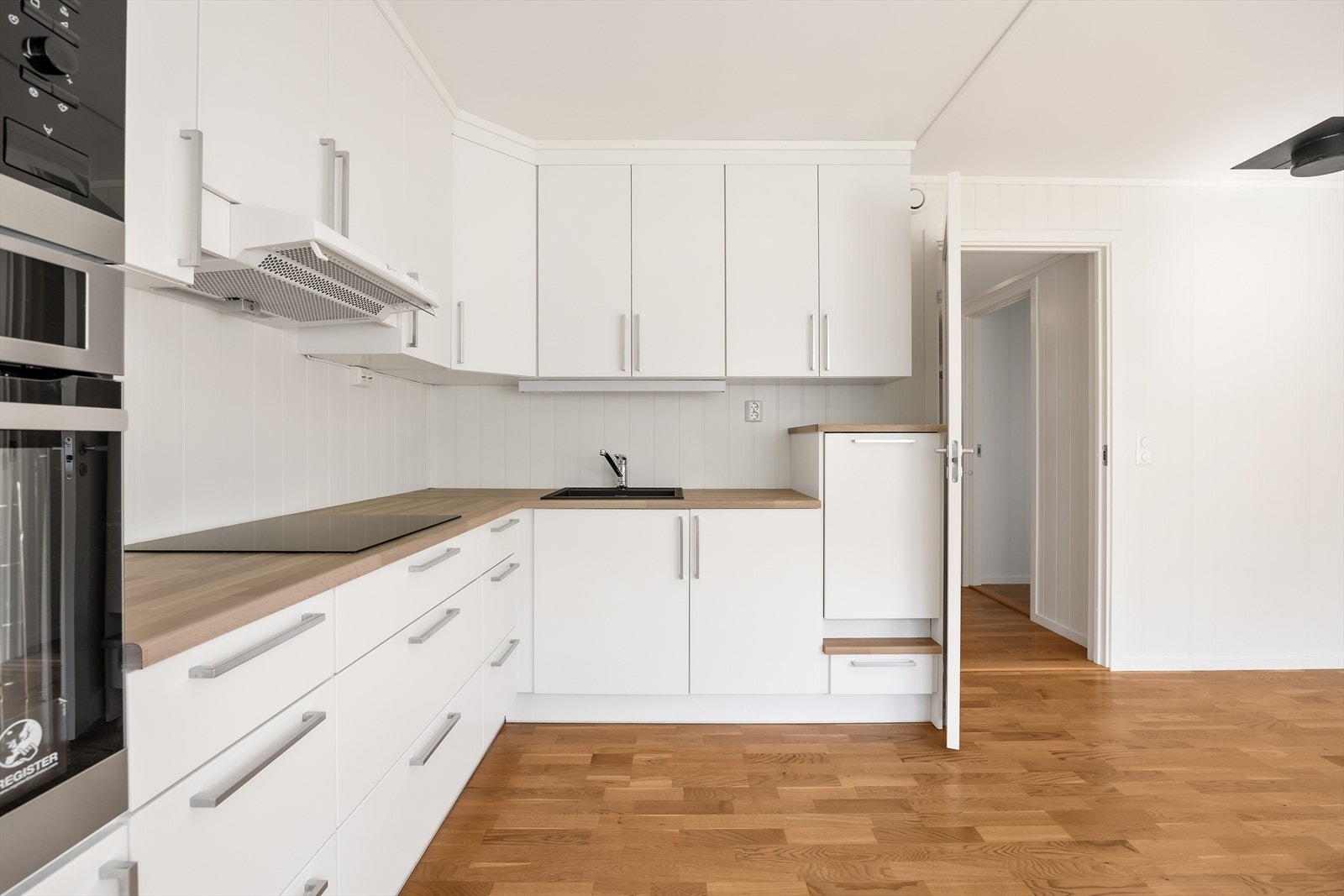 Innredningen framstår moderne og klassiske med hvite, slette fronter, laminat benkeplate og belysning under overskap. Galleribilde