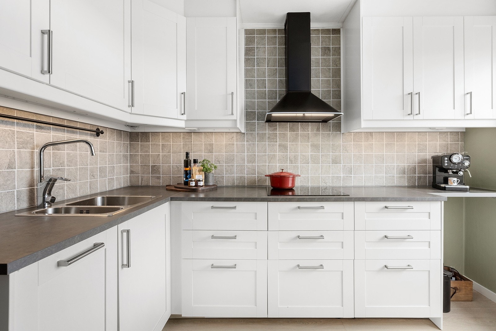 Kjøkkeninnredning med glatte folierte skapfronter, laminat benkeplate med fliser på bakvegg, 1 1/2 oppvaskkum, ventilator og innfelte hvitevarer som koketopp, stekeovn, oppvaskmaskin, kjøl/-fryseskap. Galleribilde