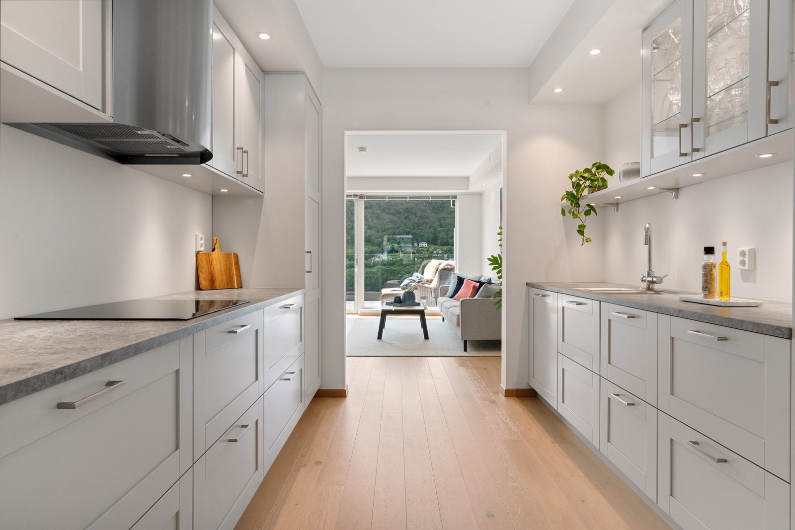 Flott kjøkkeninnredning utført i en klassisk stil med profilerte fronter, noen overskap med glassfront og benkeplate av laminat med nedfelt vask. Galleribilde
