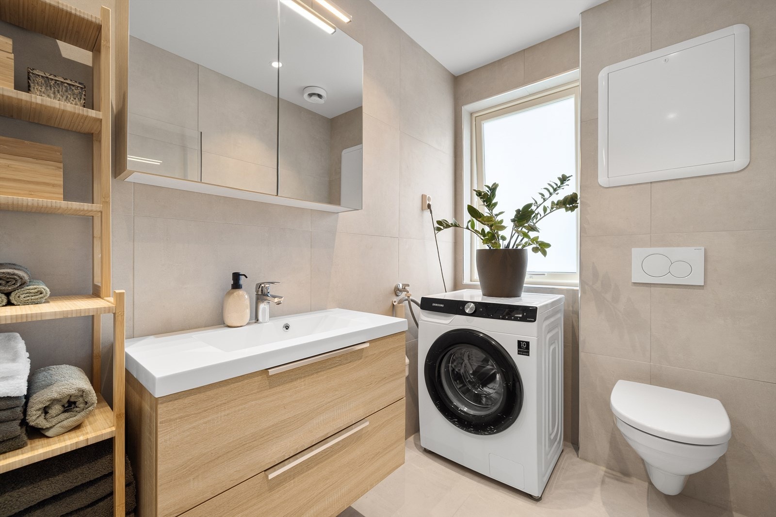 Badet er fra 2020 og inneholder servant med møblement/speilskap og belysning, vegghengt toalett, innfellbart dusjhjørne og opplegg for vaskemaskin. Galleribilde