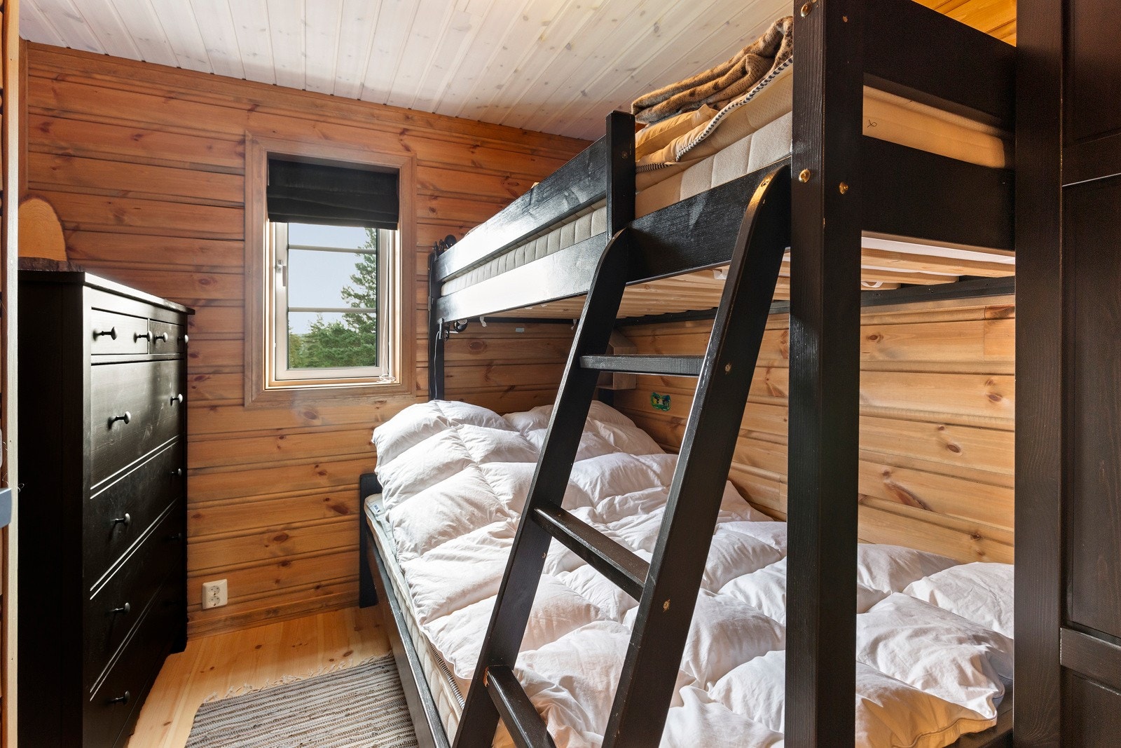 Det ene soverommet i første etasje har køyeseng med sengeplass til tre personer og høyskap med plass til oppbevaring. Galleribilde