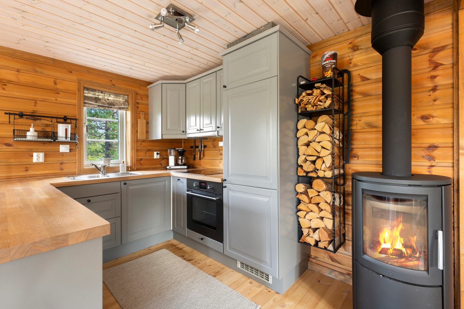 Pent grått kjøkken med profilerte kjøkkenfronter, heltre benkeplate og integrerte hvitevarer med komfyr, koketopp, kjøleskap og oppvaskmaskin Galleribilde