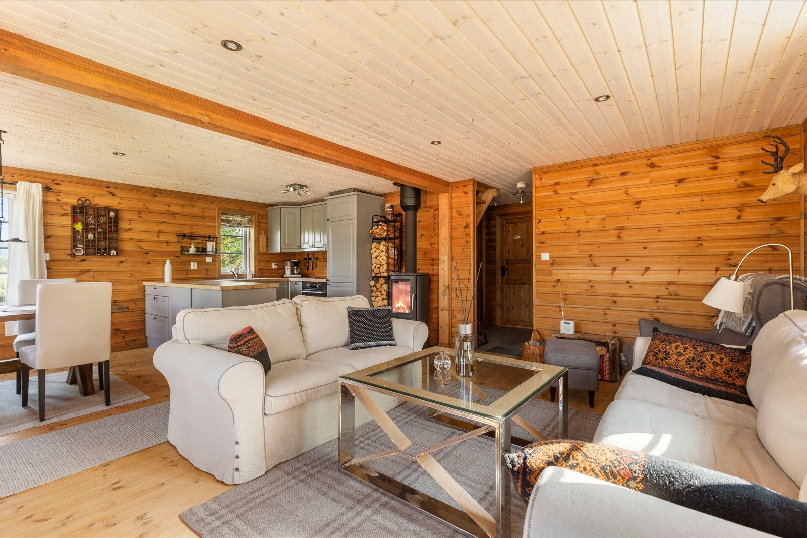 Fra gangen kommer du inn i en koselig stue med åpen kjøkkenløsning på høyre side. Rommet har furugulv og furupanel i himling og på vegger. Galleribilde