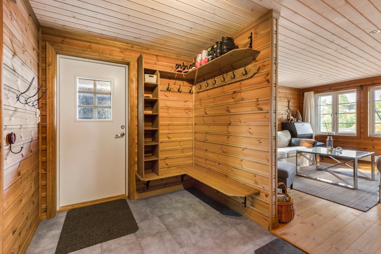 Svært romslig gang med grått flislagt gulv med varmekabler, furupanel på vegger og panel i himling med spottbelysning. Galleribilde