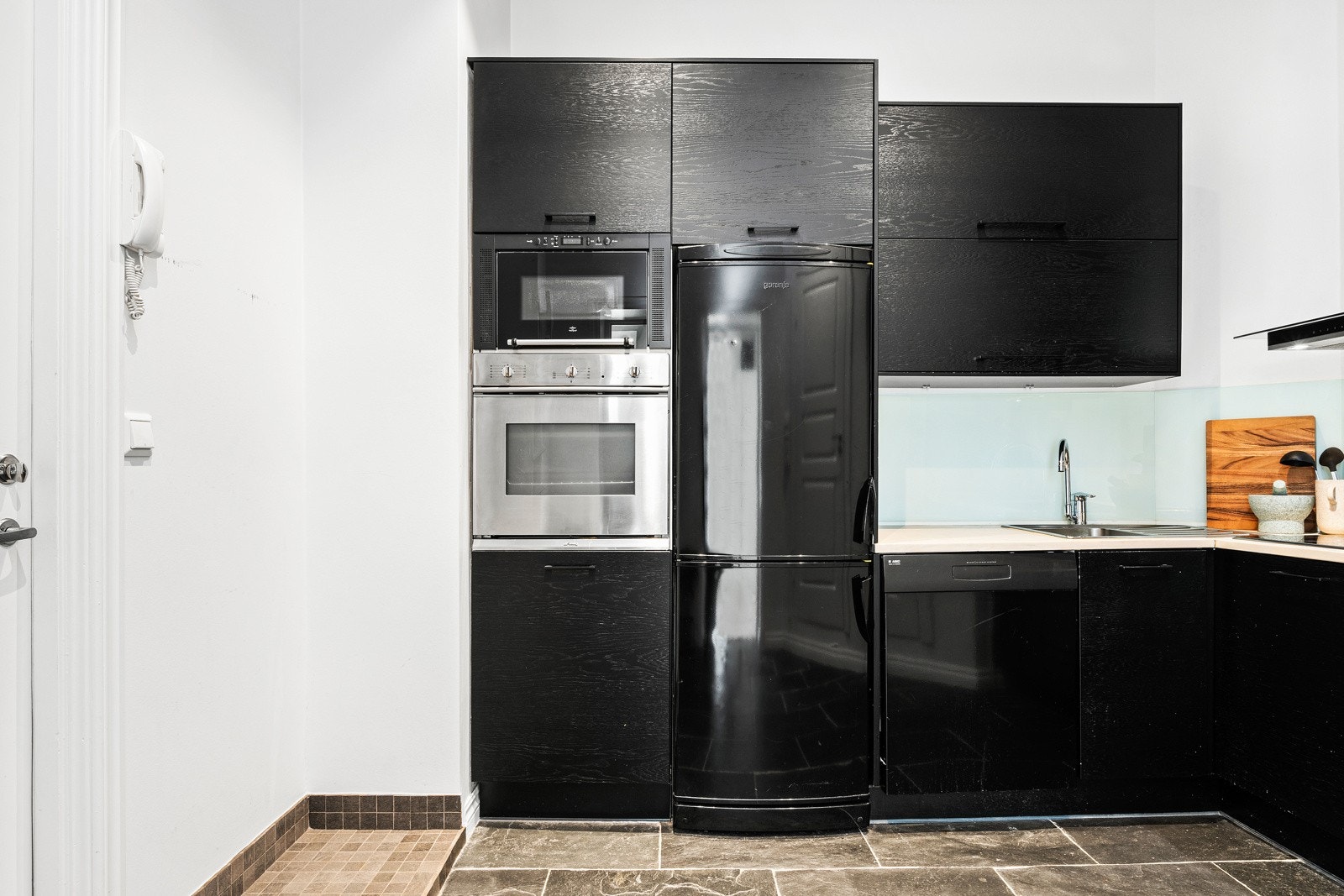 Praktisk separat kjøkken med sorte glatte fronter, laminat benkeplate med vask. Galleribilde