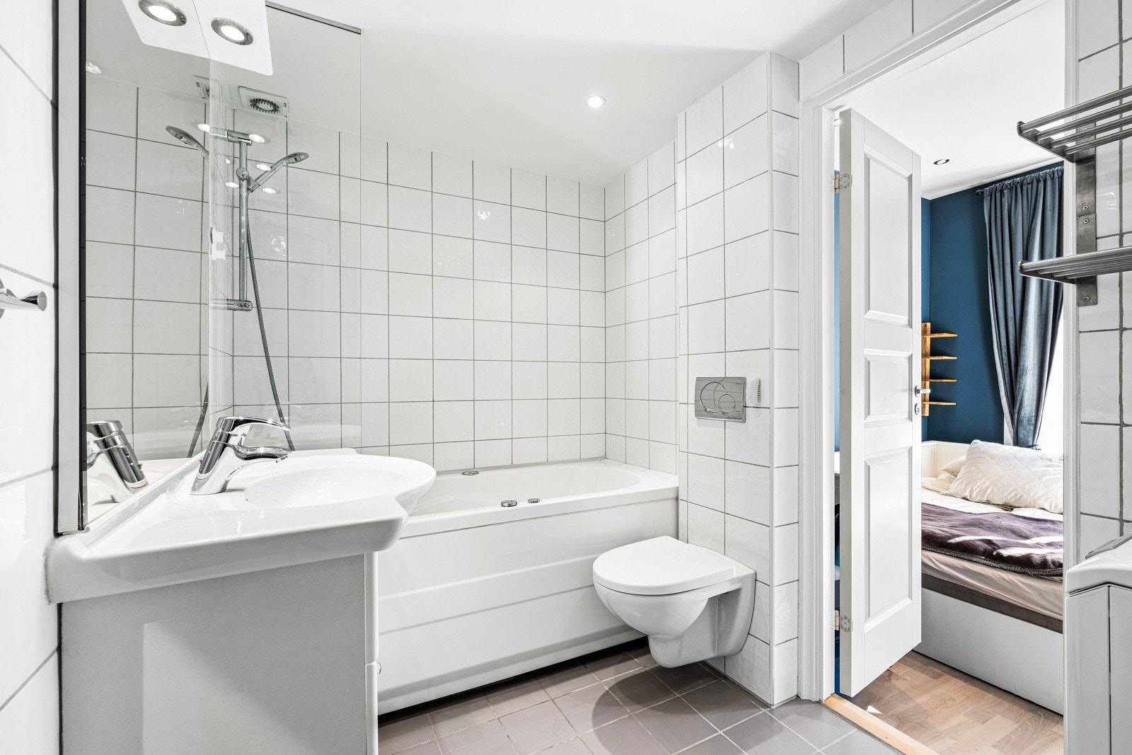 Pent, flislagt bad og har praktisk innredning med nedfelt servant, veggmontert toalett og badekar. Galleribilde