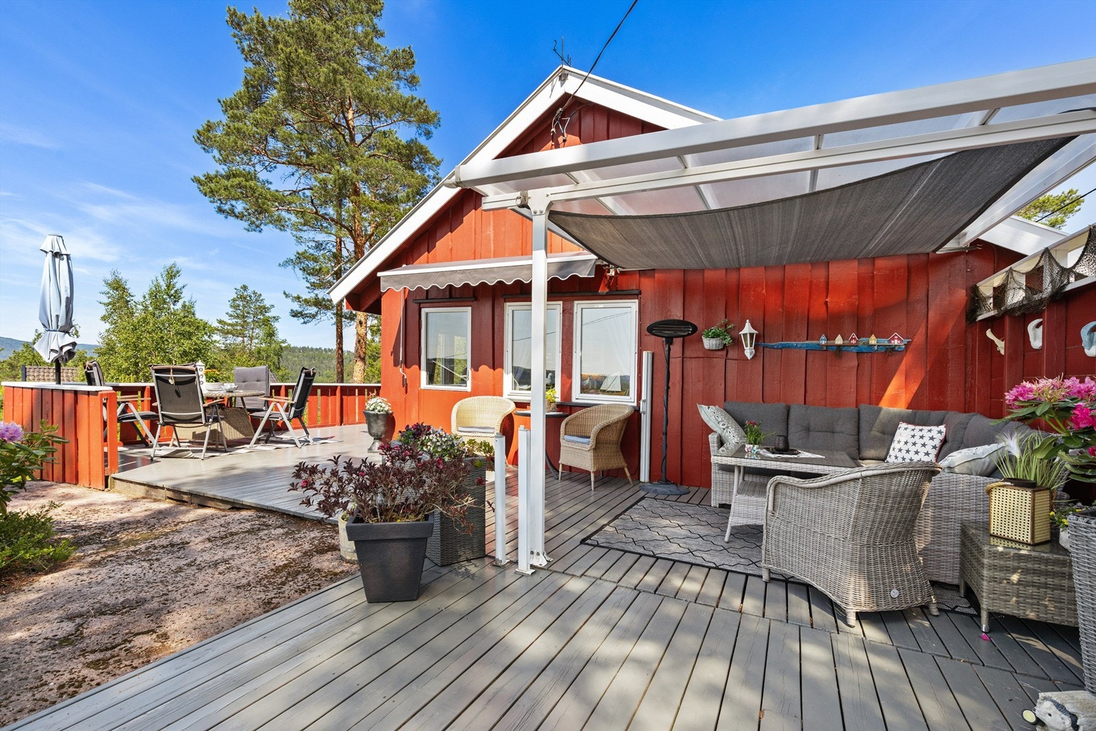 Terrassen strekker seg rundt store deler av hytta og uthuset (manglende ferdigattest på del av terrasse) Galleribilde
