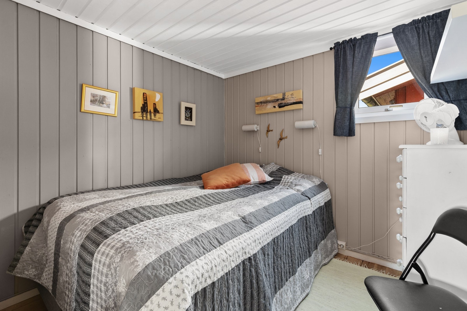 Soverom 1 med trebord på gulv, malt panel på vegger og malt panel i himling Galleribilde