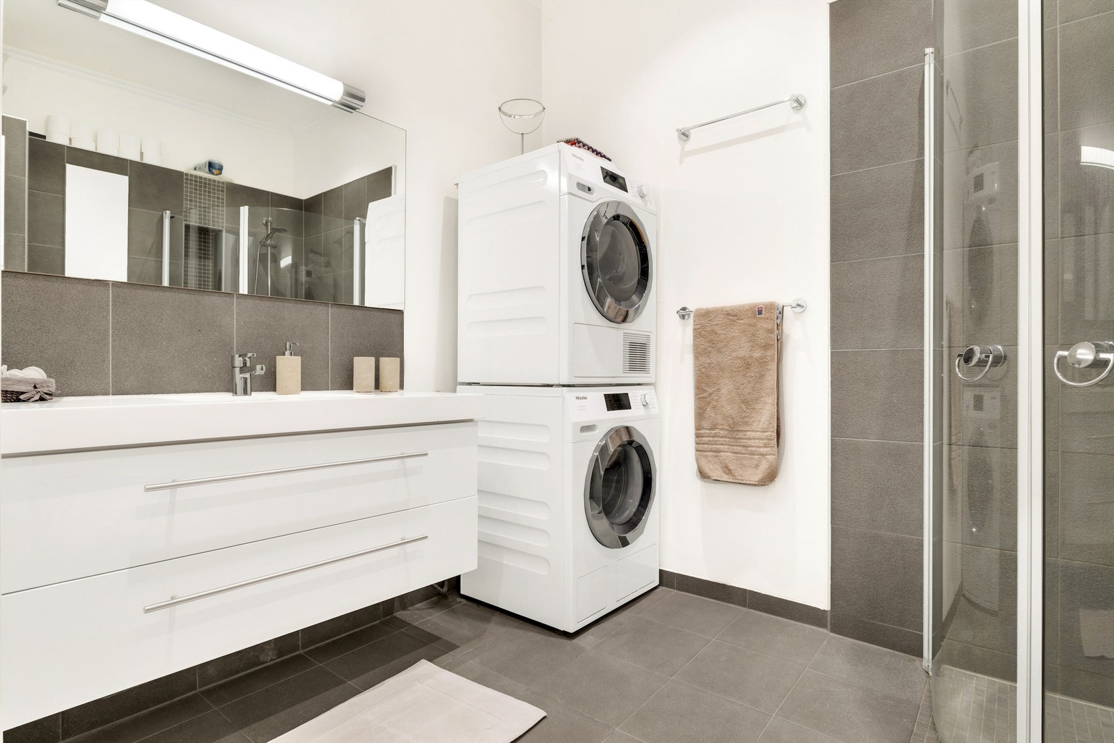 Badet er innredet med romslig servantinnredning med god oppbevaringsplass og stor speilflate, dusjhjørne og vegghengt wc Galleribilde