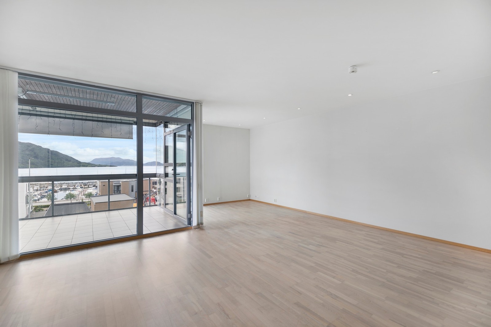 Lys og trivelig stue med parkett på gulv og tapet på vegger. Galleribilde