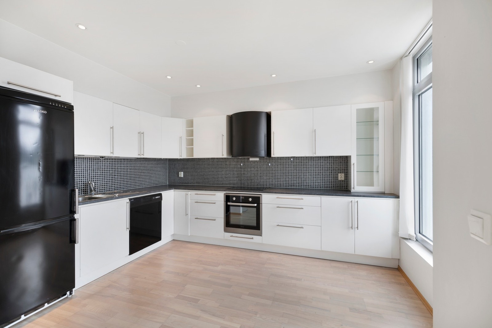 Kjøkkenet har innredning fra byggeår med hvite, slette fronter. Galleribilde