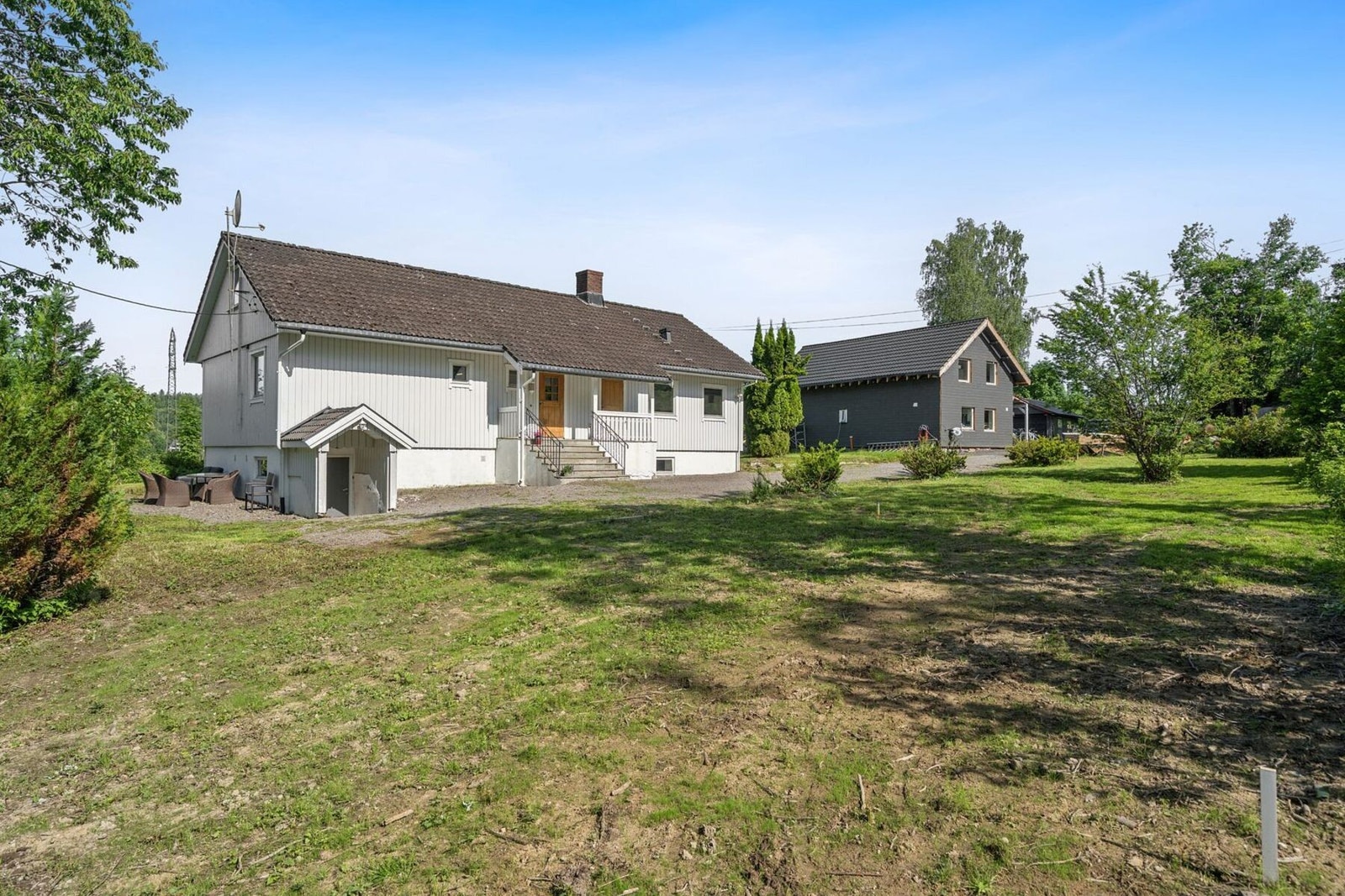 Tomten er pent opparbeidet med plen, singel og prydbusker/hekk Galleribilde