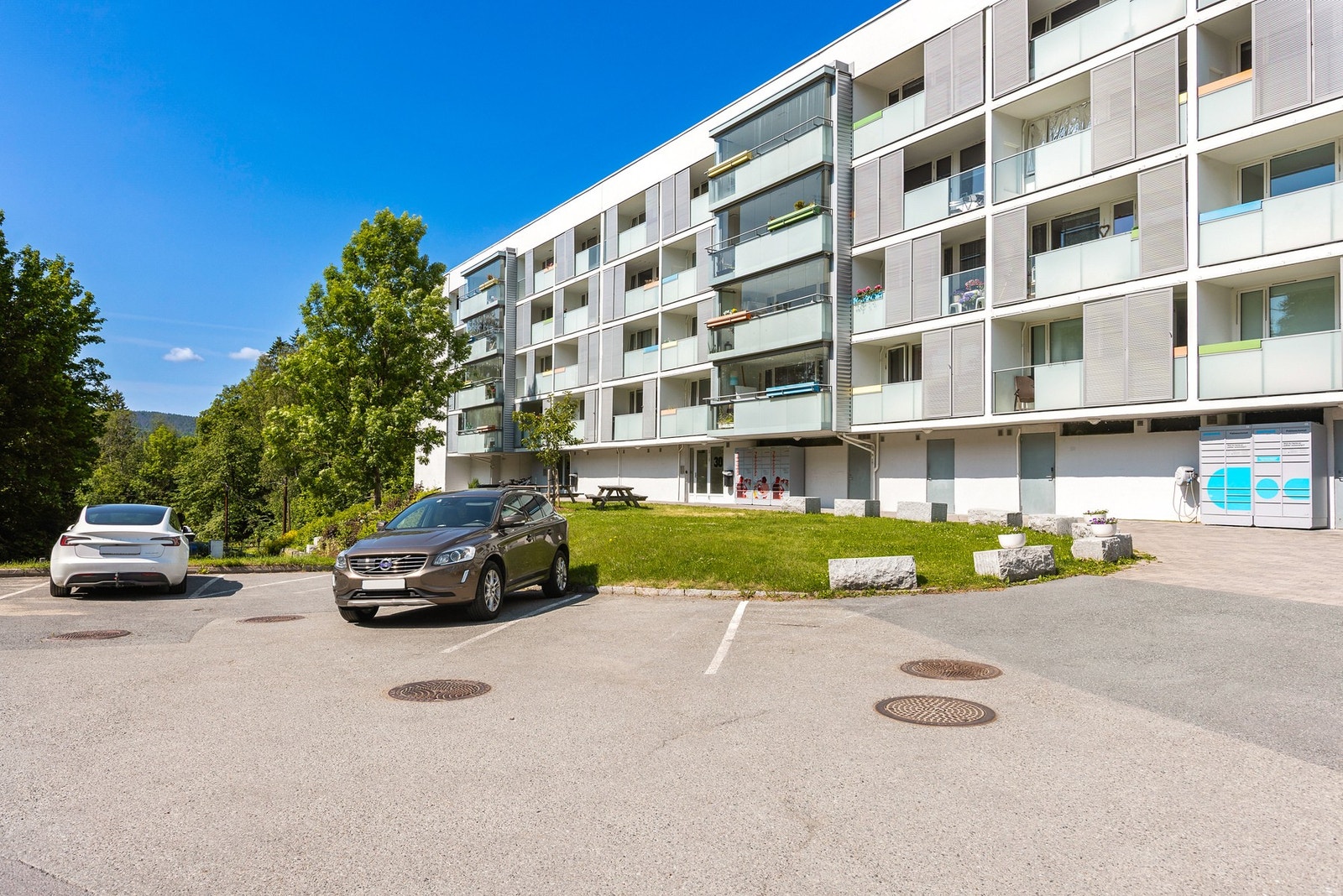 Fasade. Det medfølger egen garasje i garasjelag, samtidig er det flere parkeringsplasser for gjester. Galleribilde