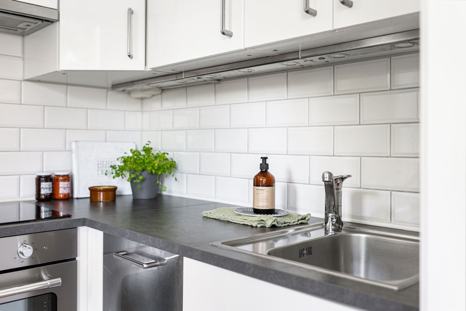 Kjøkkenet er velutstyrt med integrerte hvitevarer, bestående av oppvaskmaskin, komfyr, platetopp og kombiskap Galleribilde