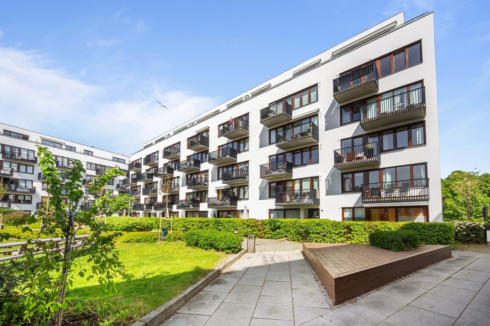 Frodig og pent opparbeidet bakhage med plen, beplantning, internveier og sittegrupper. Galleribilde