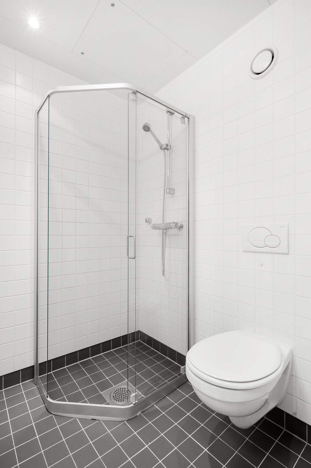 Badet er innredet med vegghengt toalett, dusjhjørne med skyvbare glassdører og nyere baderomsinnredning med nedfelt servant, skuffer og speil. Galleribilde