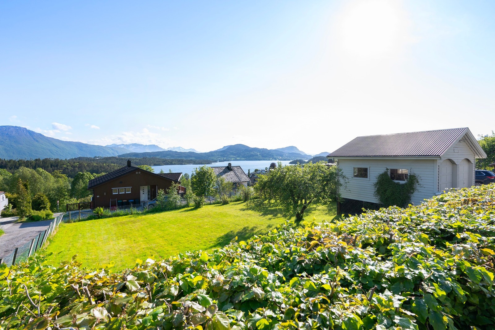 Tomten er inngjerdet med gjerde og hekk. Galleribilde