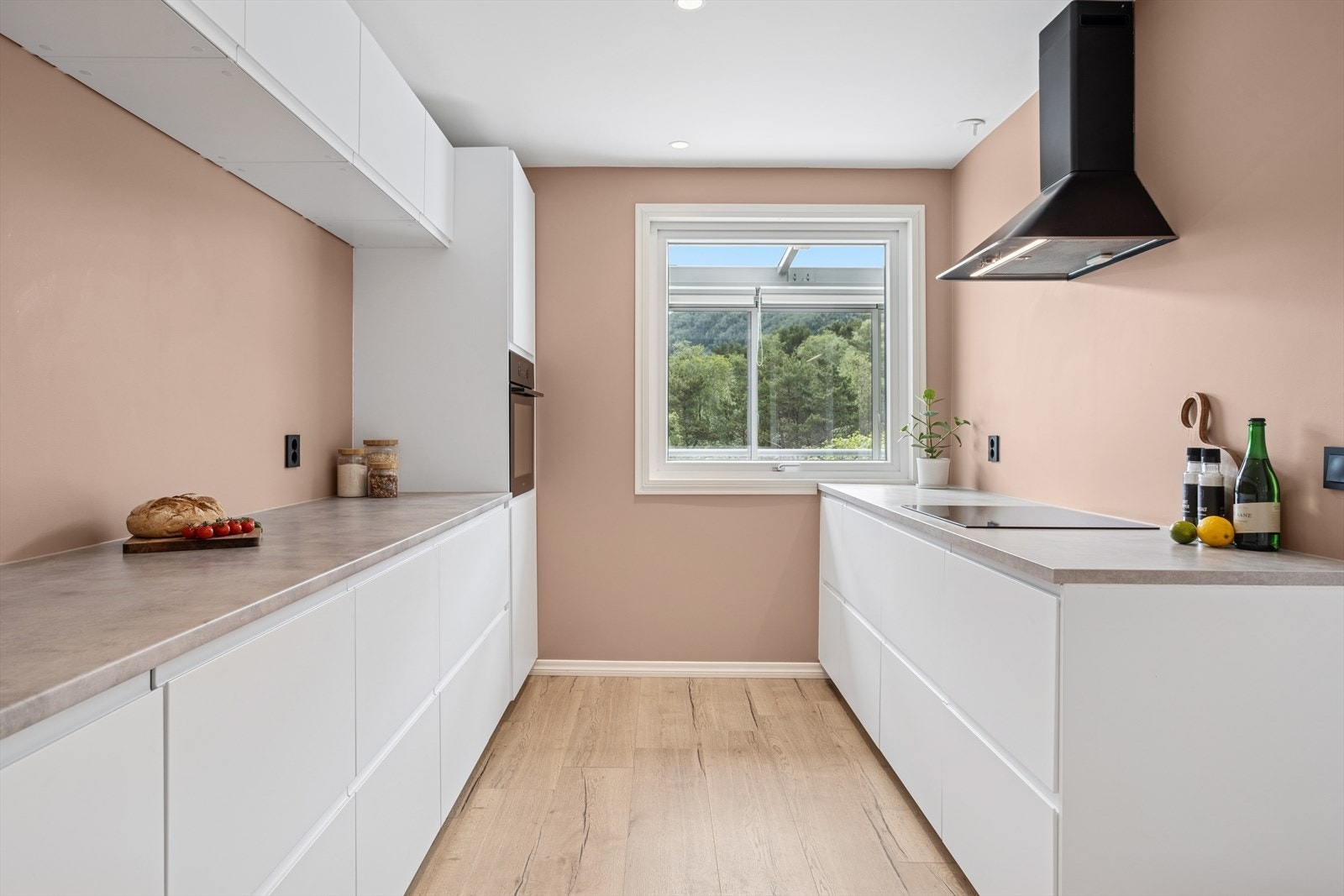 Lyst og romslig kjøkken med glatte fronter med demper og integrerte gripetak Galleribilde