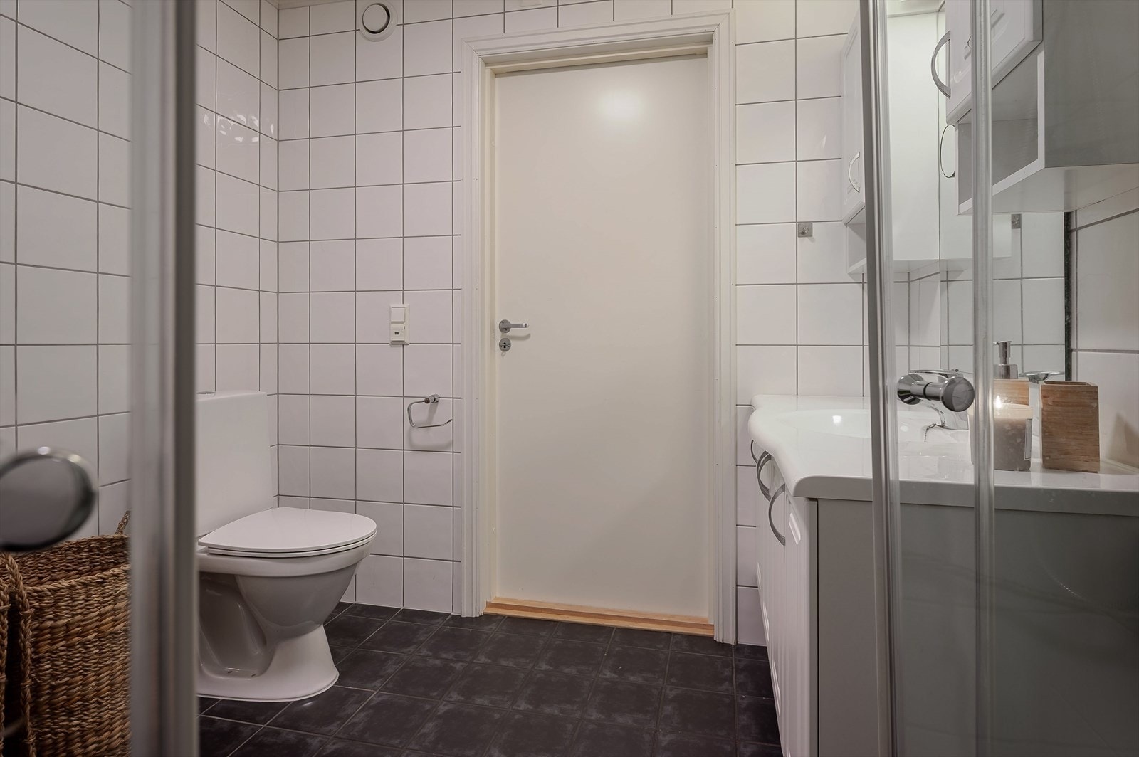 Toalett, servant med under og overskap, hjørnedusj og opplegg for vaskemaskin. Galleribilde