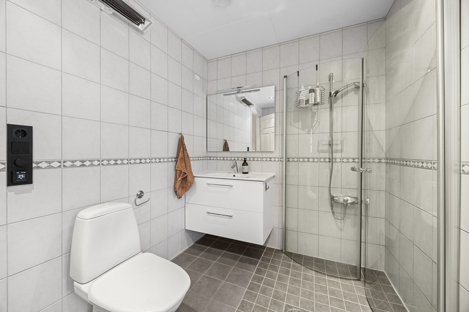 Rommet har innredning med nedfelt servant over innredning med skuffer, toalett, speil og dusjvegger/hjørne. Galleribilde