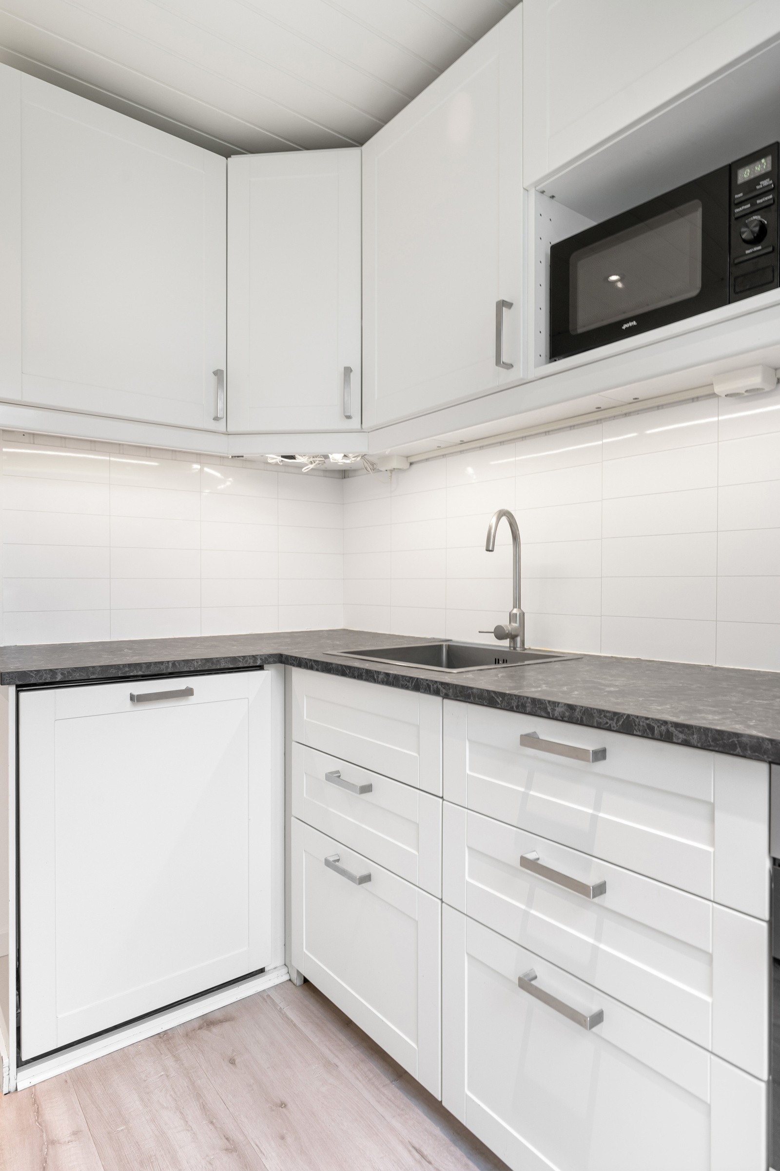 Innredningen er i en vinkel og gir godt med arbeidsplass på benkeplaten som harmonerer fint med de lyse skapene. Galleribilde