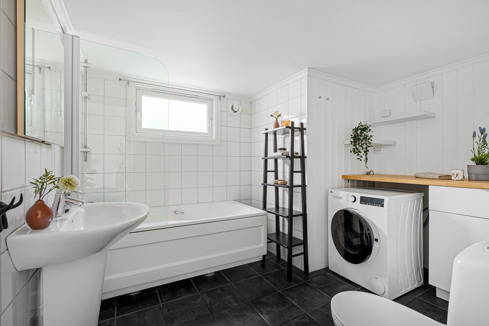 Flislagt bad med badekar, servant, toalett og opplegg for vaskemaskin - romslig og elegant. Galleribilde
