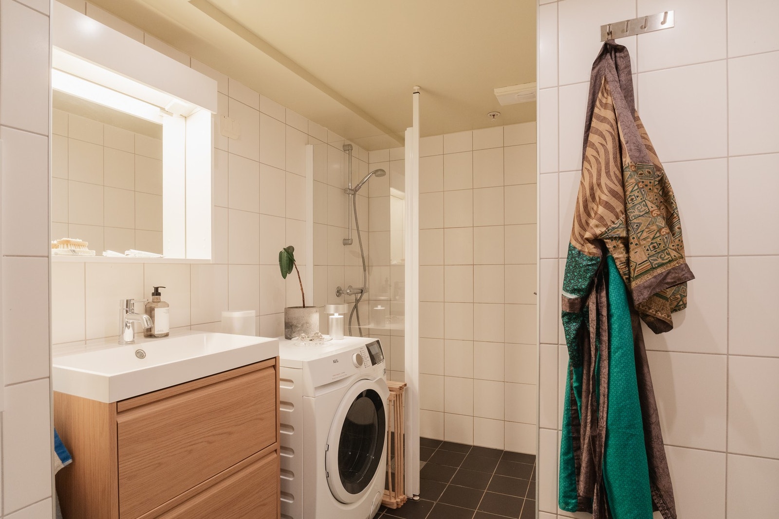 Baderommet fremstår som stilrent og funksjonelt, med tidløse flislagte overflater og behagelig komfort gjennom elektriske varmekabler i gulvet. Galleribilde