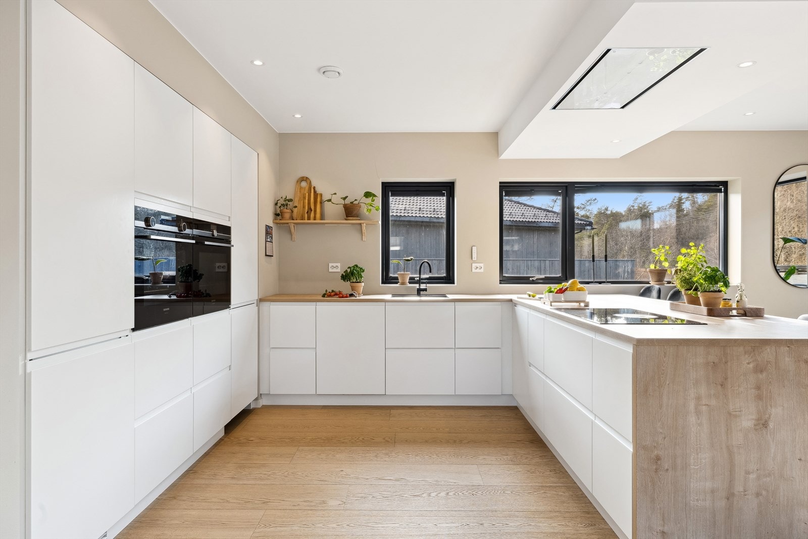 Stilrent kjøkken med integrerte hvitevarer og takmontert ventilator. Skjult spisskammers/matbod gjennom innredning. Galleribilde