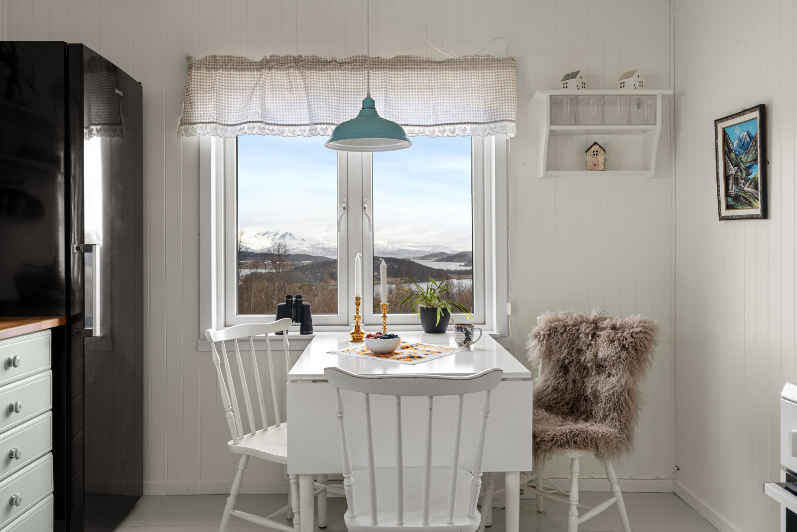 Koselig spiseplass ved vinduet og utsikt over fjord og fjell.