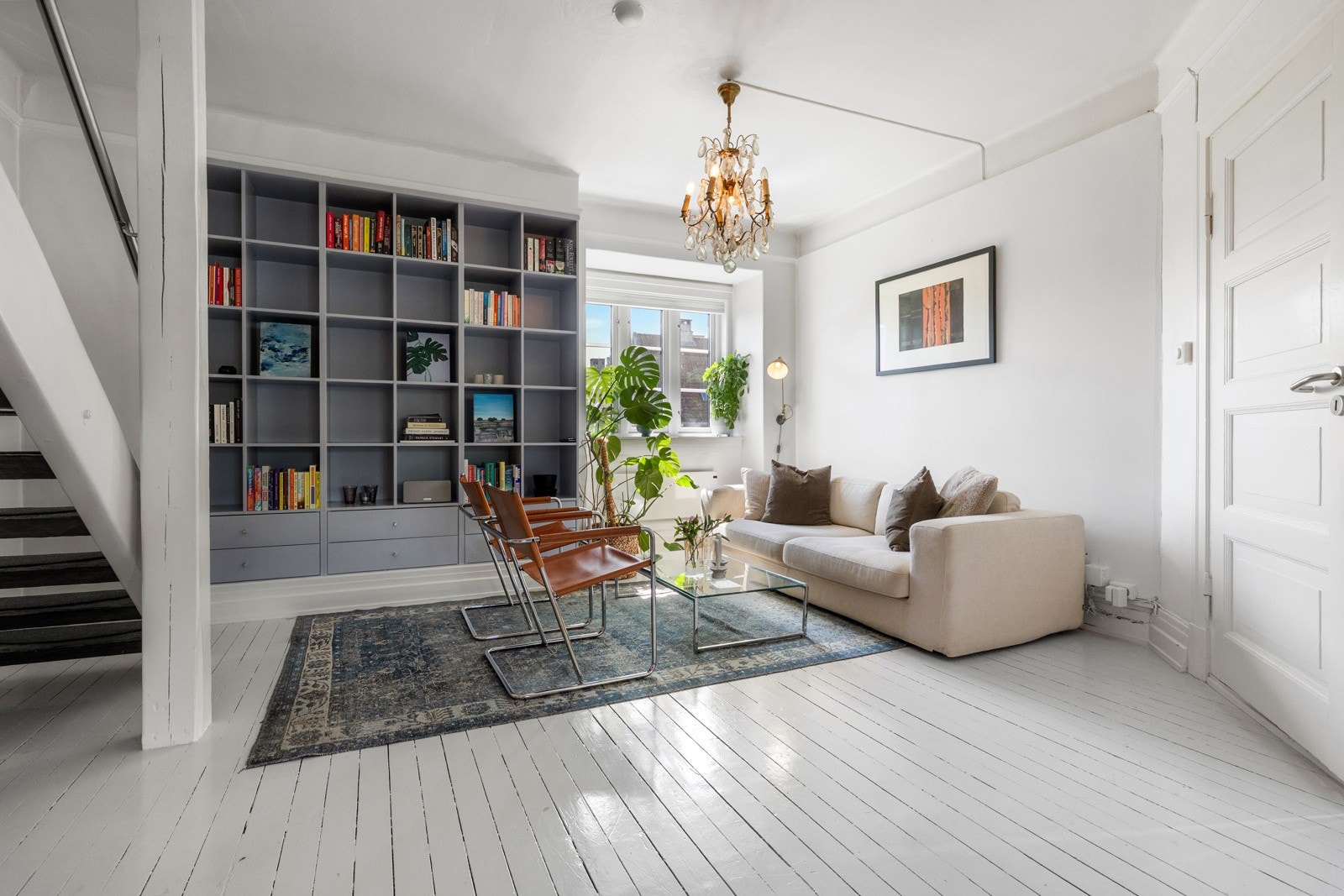 En stor og lys stue med god takhøyde samt originale gulv som er malt i lyse farger Galleribilde