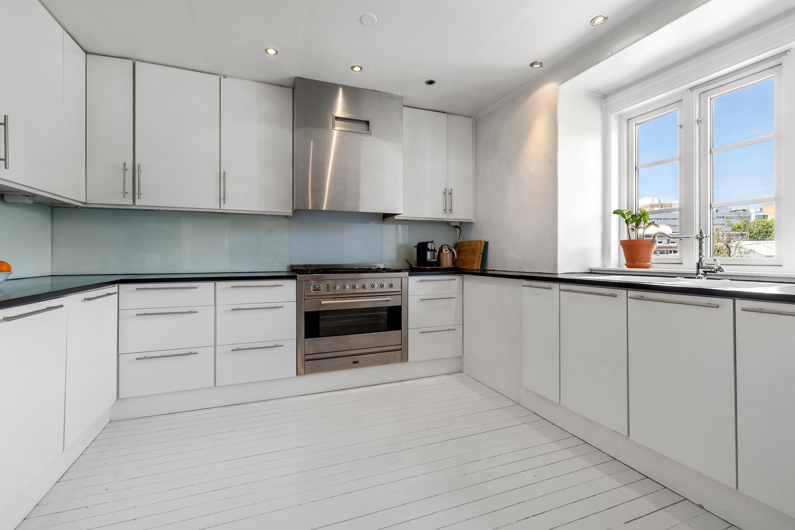 Kjøkkenet i hvit utforming og er laget i U-form, for å kunne optimalisere både skap- og benkeplass Galleribilde