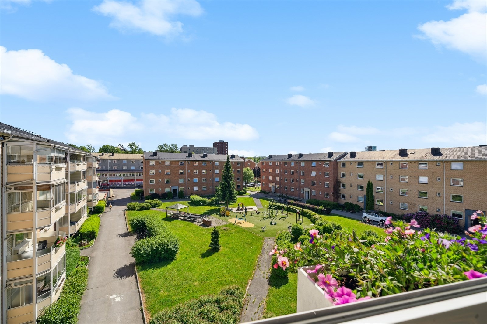 Her har du utsyn mot grønne og velstelte fellesarealer - Et rolig og hyggelig gårdsrom med lekeplass, benker og blomsterbed som skaper en trygg og innbydende atmosfære. Galleribilde
