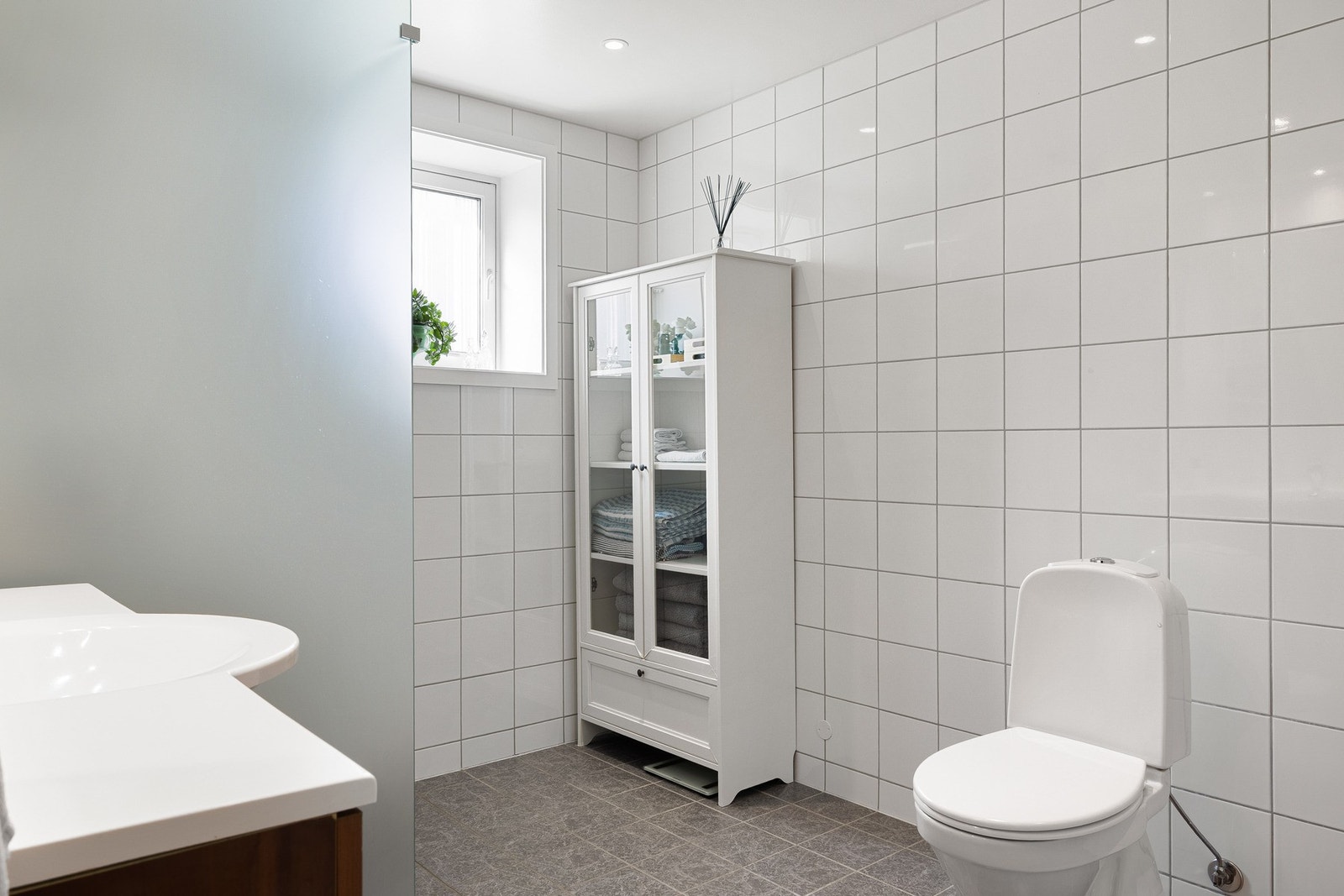 Badet er innredet med baderomsinnredning, toalett og dusj med glassvegger. Galleribilde