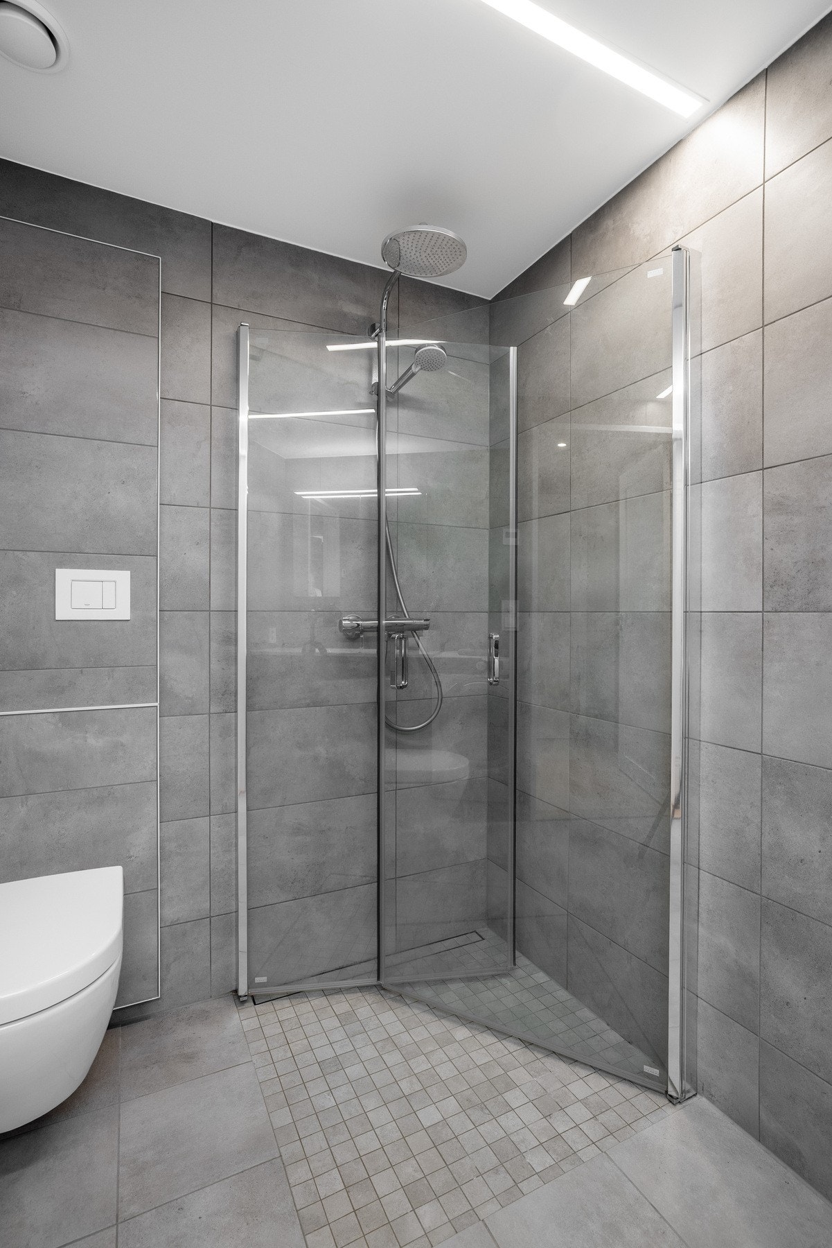 Badet består av servant, speil, dusjhjørne med innfellbare glassdører og dusjarmatur, vegghengt toalett med innebygd sisterne og opplegg for vaskemaskin. Galleribilde